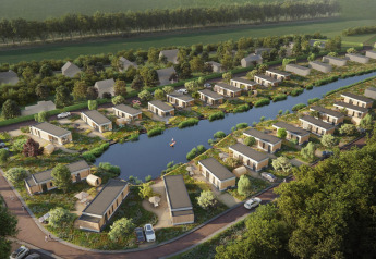 Luchtbeeld van hedendaagse lodges rond een vijver, met veel groen en geparkeerde auto's aan de huisjes.