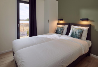 Chambre avec deux lits simples, linge de lit blanc et vue nature dans Water lodge 6 Deluxe à Hofparken Wiltershaar.