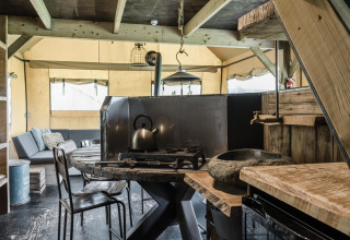 Cocina rústica y sala de estar en una cabaña, con muebles de madera, estufa de gas y sofá cómodo al fondo.