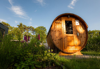 Runde Holzsauna im Freien bei Sonnenschein an der Ferienvilla Amalia, Hofparken Wiltershaar, Niederlande.