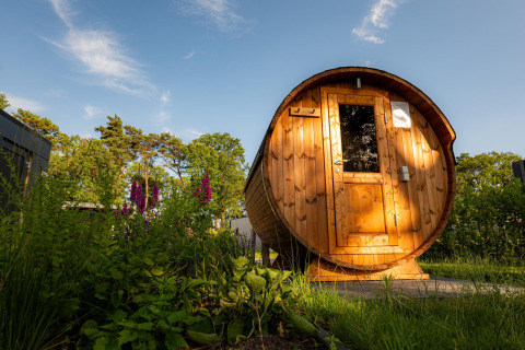 Outdoor barrel sauna in sunlight at Holiday villa Amalia in Hofparken Wiltershaar, Netherlands.
