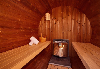 Sauna de madera en una cabaña, con bancos, toallas, un cubo de madera y un moderno calentador central.