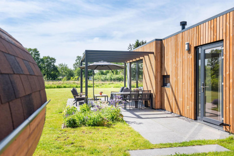 Coin salon extérieur à la Holiday villa Amalia 6 + sauna au Hofparken Wiltershaar, Pays-Bas, avec façade en bois moderne.