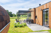 Udendørs opholdsområde ved Holiday villa Amalia 6 + sauna på Hofparken Wiltershaar, Holland, med moderne træfacade.