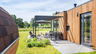 Zona de estar exterior de la Holiday villa Amalia 6 + sauna en Hofparken Wiltershaar, Países Bajos, con fachada de madera.