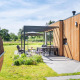 Area salotto esterna presso Holiday villa Amalia 6 + sauna a Hofparken Wiltershaar, Paesi Bassi, con facciata in legno.