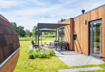 Udendørs opholdsområde ved Holiday villa Amalia 6 + sauna på Hofparken Wiltershaar, Holland, med moderne træfacade.