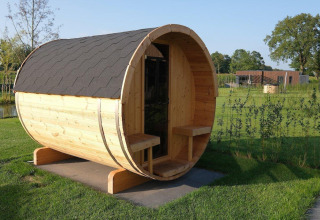 Sauna de barril de madera junto a una villa de vacaciones en el verde Hofparken Wiltershaar, Países Bajos.