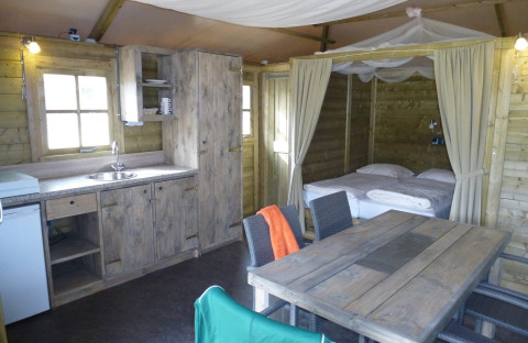 Interieur van een gezellige Camphome lodge met keuken, eettafel en bed bij Holiday park Witterzomer.