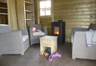 Acogedora sala de estar en una cabaña Camphome en Holiday park Witterzomer con estufa y sillones.