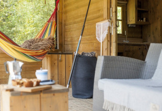 Veranda van lodge met kleurrijke hangmat, stoel en boszicht bij Camphome, Witterzomer, Nederland.