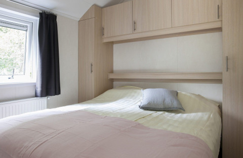 Dormitorio luminoso con cama doble y armarios empotrados en Chalet con Veranda en Holiday park Witterzomer.