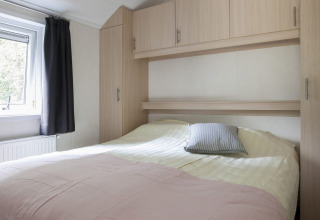 Dormitorio luminoso con cama doble y armarios empotrados en Chalet con Veranda en Holiday park Witterzomer.