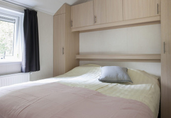 Dormitorio luminoso con cama doble y armarios empotrados en Chalet con Veranda en Holiday park Witterzomer.
