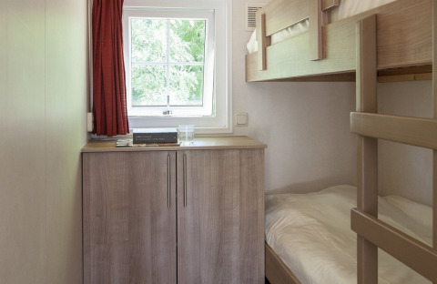Dormitorio pequeño con literas, armario de madera, ventana y cortina roja en la Lodge de Witterzomer.