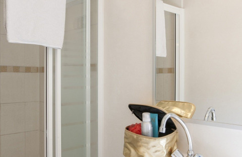 Bagno con doccia, asciugamano bianco e beauty case nella Lodge presso Holiday park Witterzomer, Paesi Bassi.