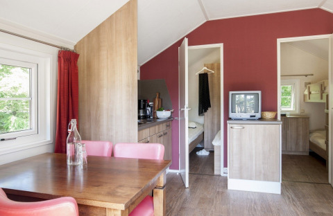 Innenansicht einer Lodge im Holiday Park Witterzomer in den Niederlanden, mit Essecke und Schlafzimmern.