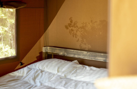 Innenaufnahme eines Safari-Zeltes im Holiday Park Witterzomer, Niederlande, mit Bett und Sonnenlicht.