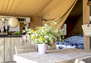 Intérieur d'une tente safari au Holiday park Witterzomer, Pays-Bas, avec déco rustique, cuisine et bouquet.