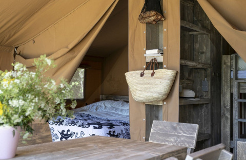 Interno di una tenda Safari all’Holiday park Witterzomer nei Paesi Bassi, con mobili in legno e fiori.
