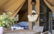 Interno di una tenda Safari all’Holiday park Witterzomer nei Paesi Bassi, con mobili in legno e fiori.