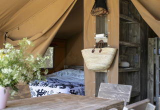 Intérieur d’une tente safari au Holiday park Witterzomer, Pays-Bas, avec mobilier en bois et fleurs.