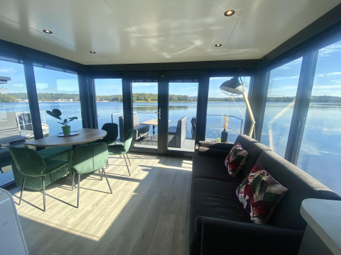 Salón moderno en Houseboat Marina Mookerplas con amplios ventanales y vistas espectaculares al lago tranquilo.