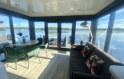 Salón moderno en Houseboat Marina Mookerplas con amplios ventanales y vistas espectaculares al lago tranquilo.