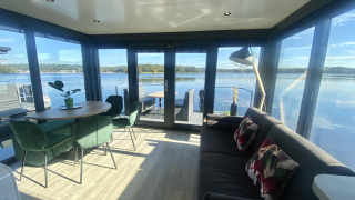Moderne leefruimte op Houseboat Marina Mookerplas met grote ramen en prachtig uitzicht over het meer.