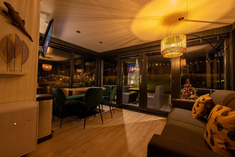 Acogedor salón en la Houseboat Marina Mookerplas, decorado con luces festivas y un árbol de Navidad iluminado.