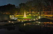 Foto nocturna de Houseboat Marina Mookerplas con luces navideñas, árbol y reflejos en el agua.
