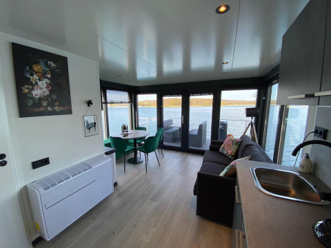 Sala de estar moderna y cocina en Houseboat Marina Mookerplas con grandes ventanales y vista al lago