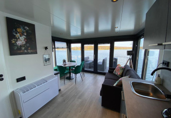 Soggiorno moderno e cucina su Houseboat Marina Mookerplas con grandi finestre e vista sul lago