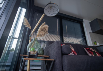 Moderne stue på Houseboat Marina Mookerplas med sofa, pyntepuder, planter og store vinduer.