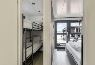 Interior de una casa flotante con una habitación de literas a la izquierda y una de cama doble a la derecha.