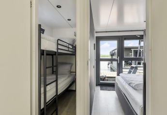 Interior de una casa flotante con una habitación de literas a la izquierda y una de cama doble a la derecha.