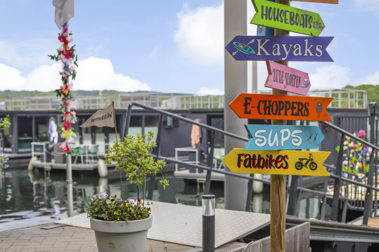 Cartel colorido en Houseboat Marina Mookerplas que indica actividades como kayaks, SUPs y fatbikes.