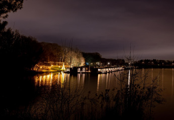 Vista notturna dell’Houseboat Marina Mookerplas nei Paesi Bassi, houseboat illuminate riflesse sull’acqua.