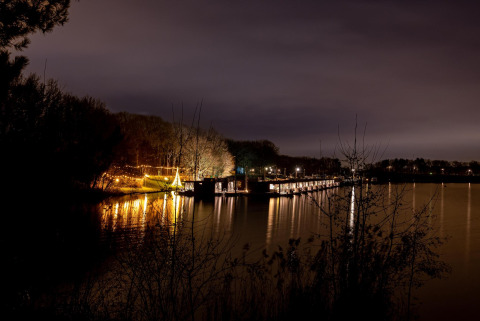 Nachtaufnahme von Houseboat Marina Mookerplas in den Niederlanden, beleuchtete Hausboote am Wasser.