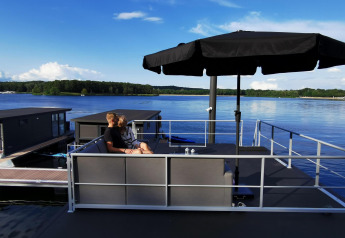 Una coppia seduta sotto un ombrellone nero sulla terrazza di una houseboat a Marina Mookerplas, Paesi Bassi.