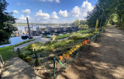 Vista de Houseboat Marina Mookerplas en los Países Bajos con casas flotantes, flores y camino junto al agua.
