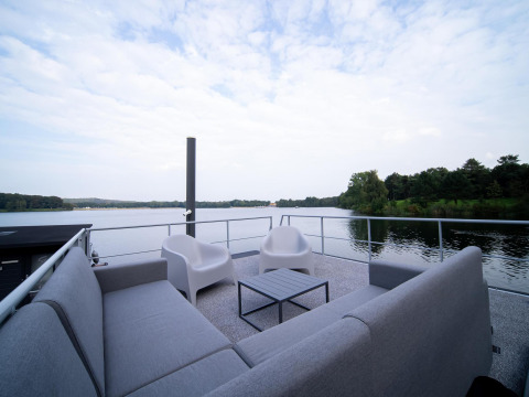Zona de asientos en la cubierta del Houseboat Marina Mookerplas con vistas al agua y naturaleza en Holanda.