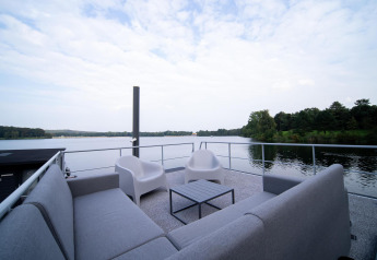 Zona soggiorno sul ponte di Houseboat Marina Mookerplas con vista sul lago e natura in Olanda.