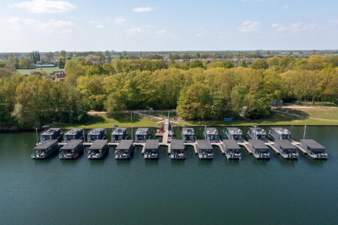 Vista aerea delle houseboat alla Marina Mookerplas nei Paesi Bassi, ormeggiate vicino alla riva alberata.