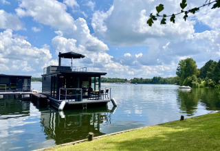 Moderne husbåd ved marinaen med solrig himmel og rolige vande på Marina Mookerplas, Holland.