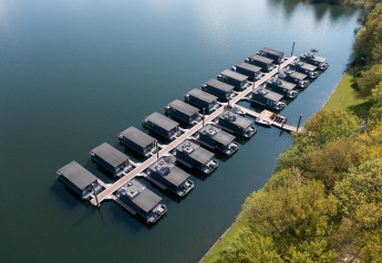 Luchtfoto van Houseboat Marina Mookerplas in Nederland, met meerdere woonboten aangemeerd aan de steiger.