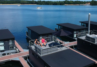 Zwei Personen entspannen sich auf dem Dach eines Hausboots in der Marina Mookerplas, Niederlande.