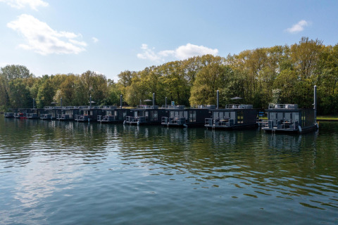 Varios barcos-casa modernos atracados en la Marina Mookerplas, rodeados de vegetación junto al agua en Holanda.