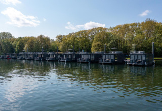 Varios barcos-casa modernos atracados en la Marina Mookerplas, rodeados de vegetación junto al agua en Holanda.