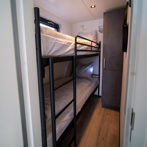 Dormitorio estrecho con literas y armario en Houseboat Heeg en Marina Heeg, Países Bajos, visto desde la puerta.